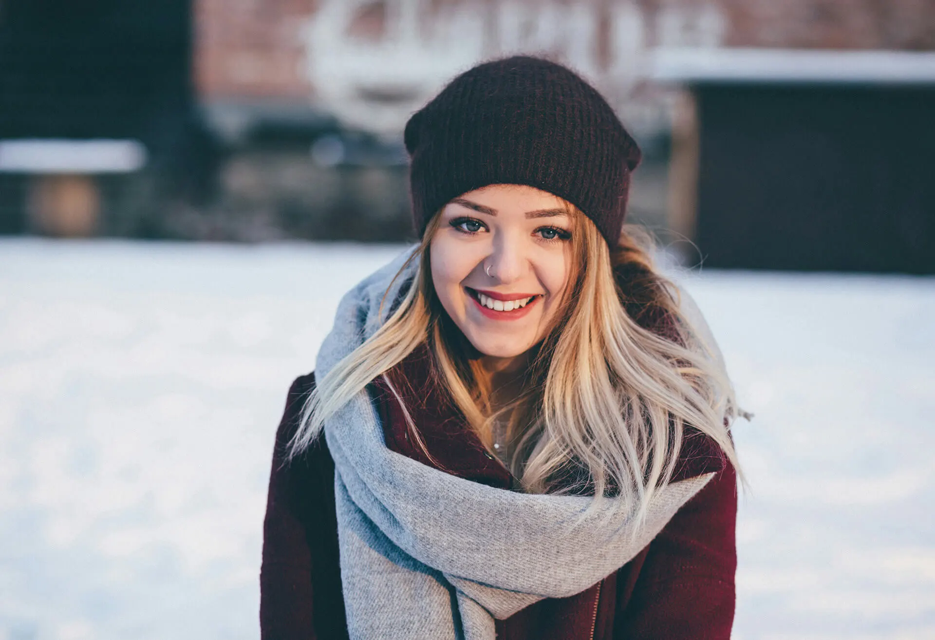 young woman smiling at the camera wearing winter clothes and a toque