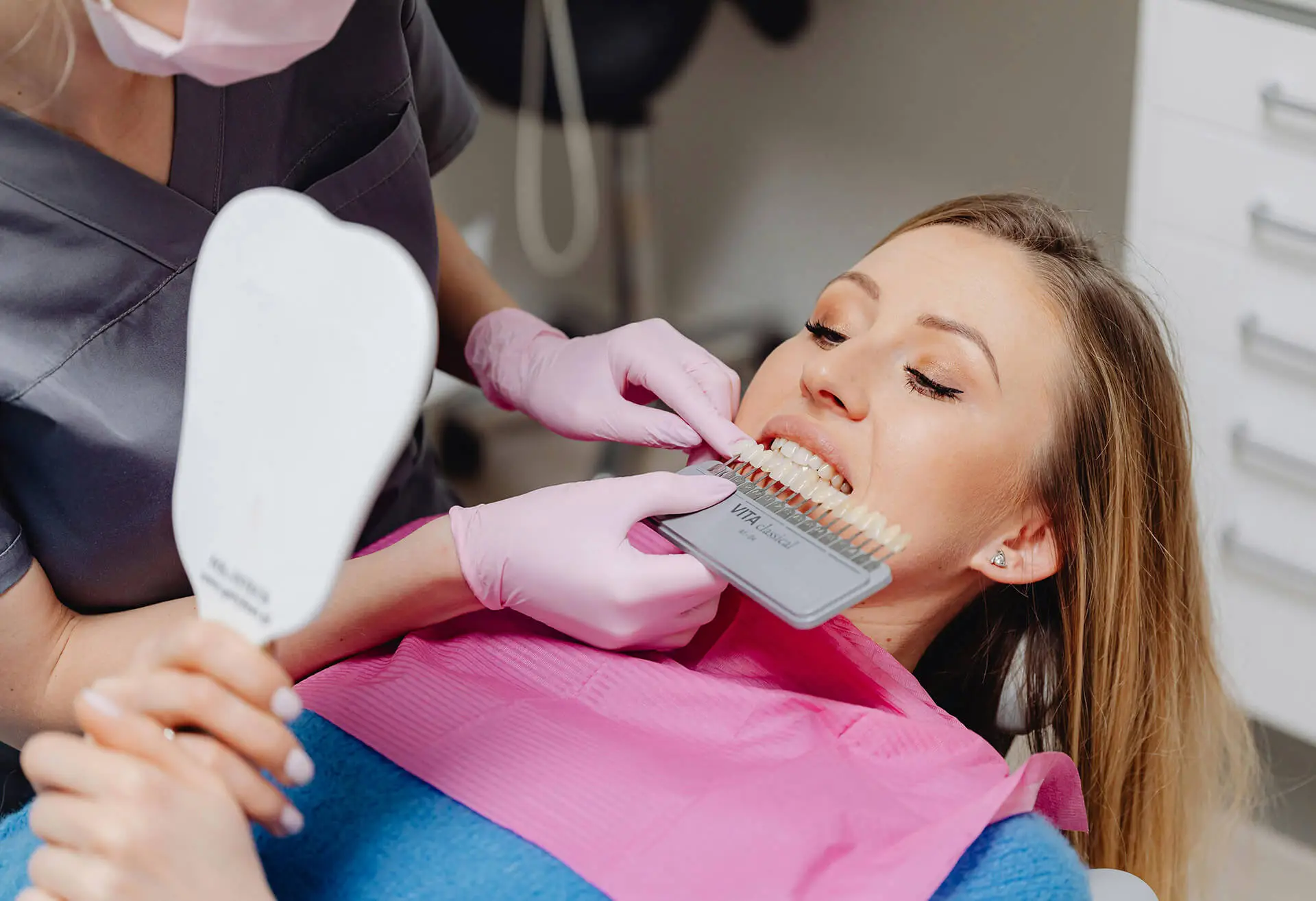 a patient getting her natural teeth colour matched by a dentist for her new dental veneers