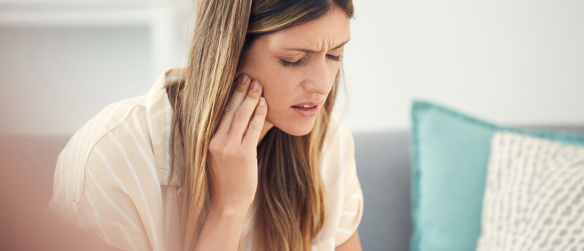 a woman with aching tooth holding her jaw in pain