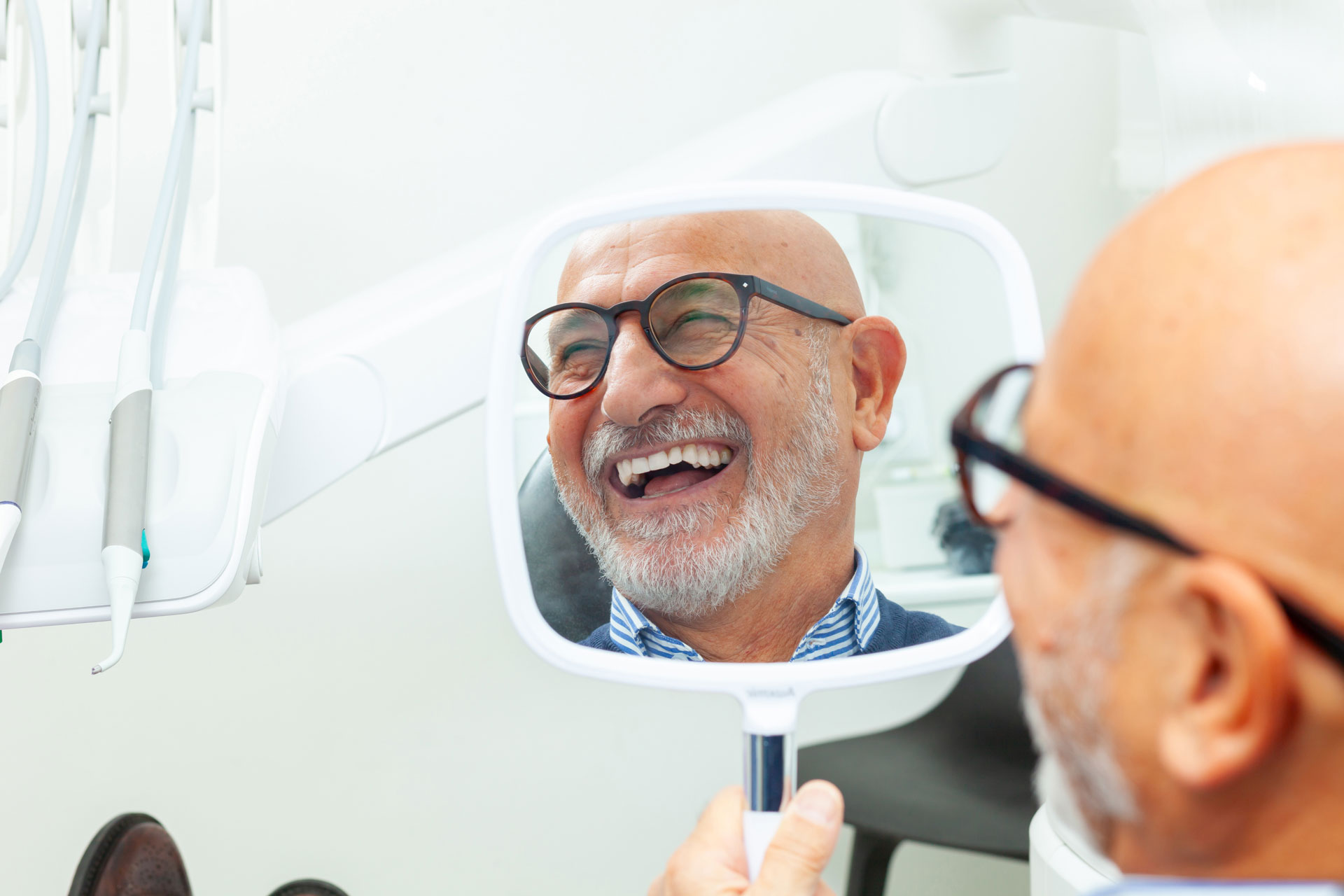 Man smiling holding a hand held mirror