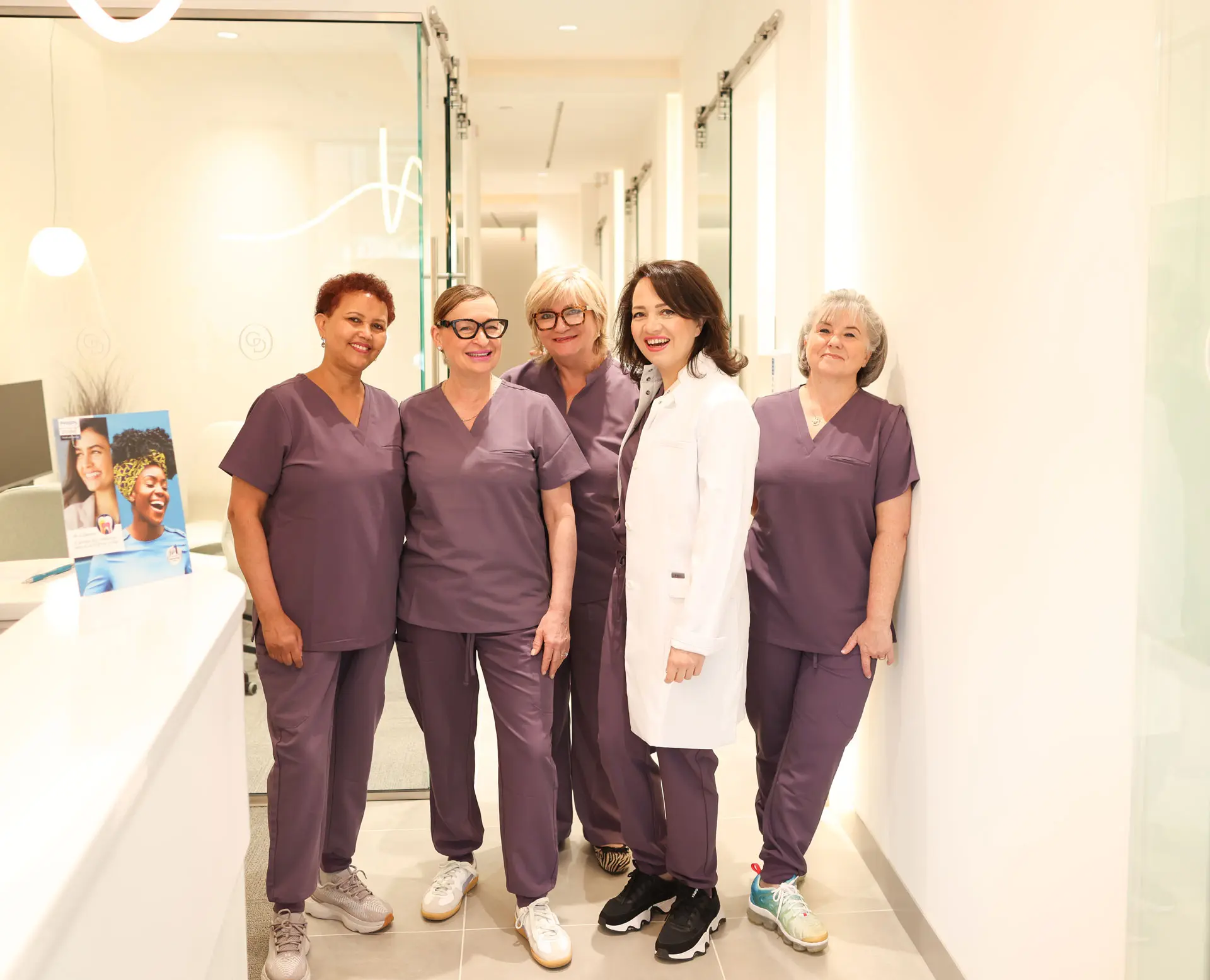 team of qualified, compassionate dentists at GLEAM Dental at the Toronto dental clinic's front desk area, along with founder and general dentist, Dr Lidiya