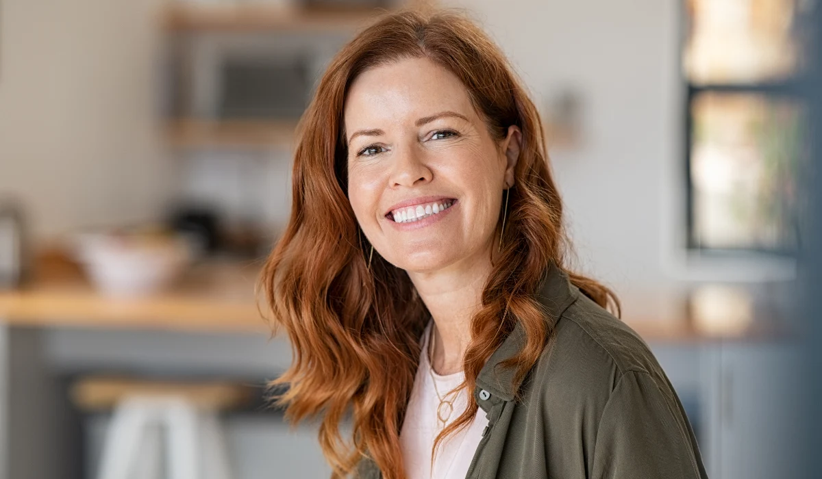 Smiling red haired woman sitting indoors