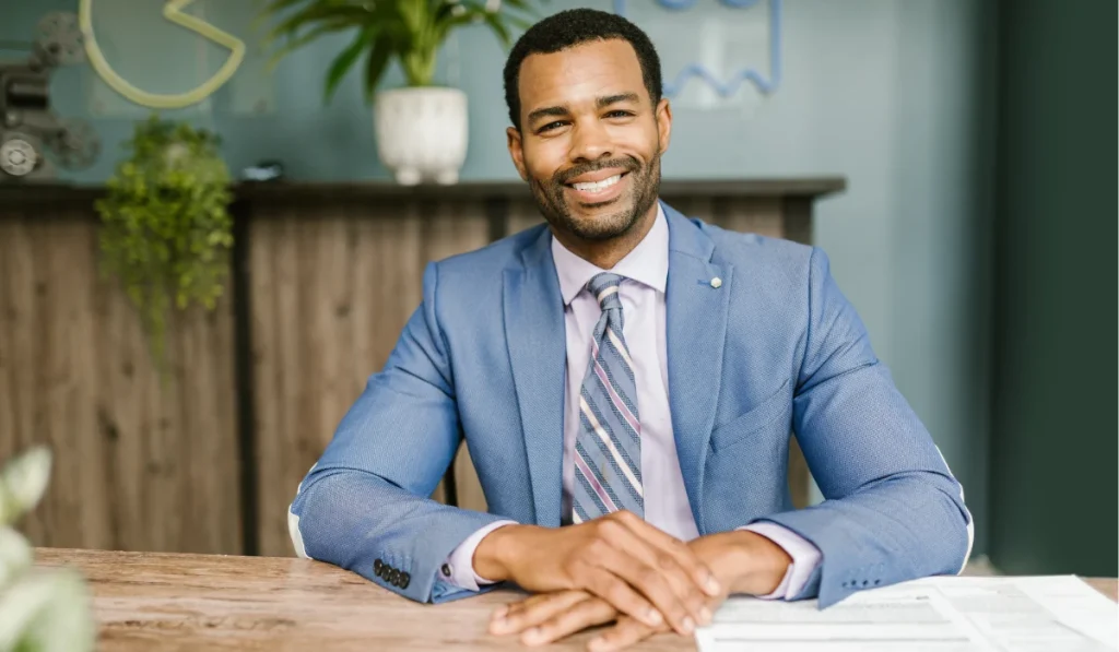 Smiling man in a blue suit seated at a desk